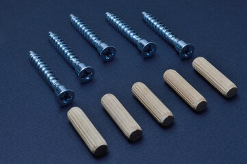 furniture screw and wooden dowel. lie on a dark background. close-up.
