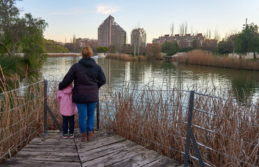 Mujer y ni&ntilde;a observando el atardecer  tranquilo en el lago del parque de cabecera de Valencia