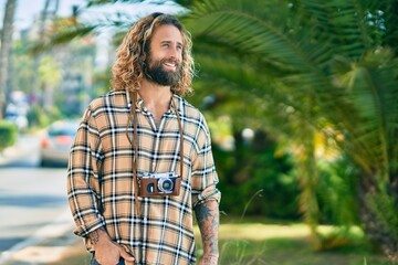 Young caucasian tourist man smiling happy using vintage camera at the park.