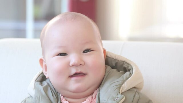 Slow motion of a lovely 9 months asian baby smiling and playing, 4k