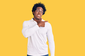Handsome african american man with afro hair wearing casual clothes and glasses pointing aside...