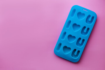 top view of blue silicone mold for ice or candies in shape of phrase I love you for handmade dessert on valentine day gift. pink background. concept of Valentine's Day, Love and Mother day. copy space