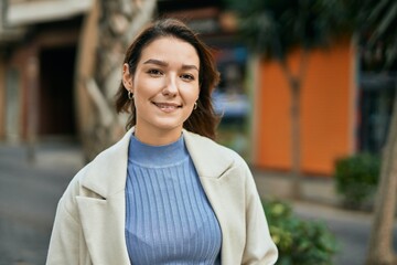 Young hispanic woman smiling happy standing at the city