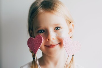 Lovely little girl with paper hearts. Valentines day. Portrait of a child holding pink valentine. - 406207250