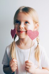 Lovely little girl with paper hearts. Valentines day. Portrait of a child holding pink valentine. - 406207265