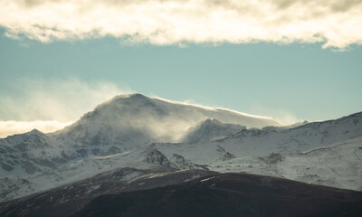 Peaks of Sierra Nevada in Granada (Spain) at sunrise between clouds on a winter morning