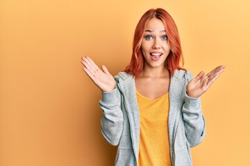 Young beautiful redhead woman wearing casual sporty sweatshirt celebrating victory with happy smile and winner expression with raised hands