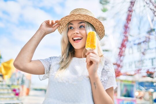 Young caucasian tourist girl smiling happy and eating ice cream at fairground.