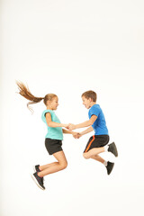 Adorable kids holding hands and jumping against white background