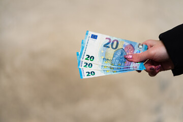 Woman hand holding or giving money like a bribe or tips. World money concept, close up of 20 EURO...
