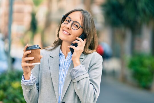 Young hispanic businesswoman talking on the smartphone and drinking take away coffee at the city.