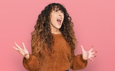 Young hispanic girl wearing casual clothes crazy and mad shouting and yelling with aggressive...