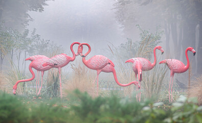 Fototapety  sculptures of flamingos in the park misty morning installation reeds grass trees