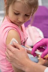 The doctor is giving a little girl an injection. The child stares in a choking bowl. Preventive...