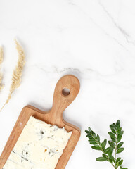 gorgonzola cheese on a wooden board. composition on a marble table. look from above.