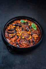 Modern style slow cooked Lebanese vegetarian eggplant stew maghmour served with chickpeas as close-up in a design pot with copy space