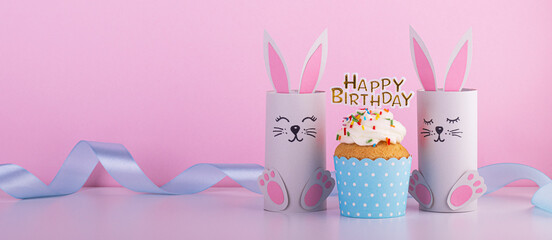Cute paper rabbits from a roll of toilet paper with the cake on his birthday. Background for the birthday party