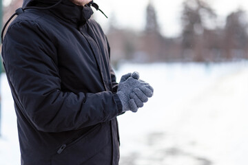 The guy in gloves warms his hands. The guy warms his hands. Hands in gray winter gloves. The palm...