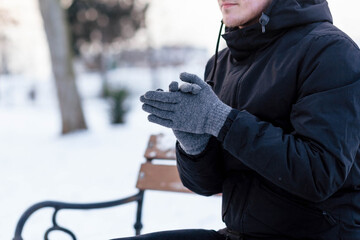 The guy in gloves warms his hands. The guy warms his hands. Hands in gray winter gloves. The palm...