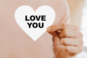 Man holding a love card in the shape of a heart with love you