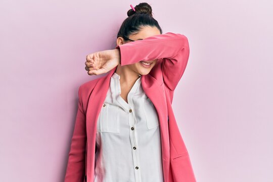 Beautiful middle eastern woman wearing business jacket and glasses covering eyes with arm smiling cheerful and funny. blind concept.