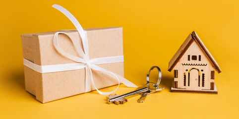 House miniature model, gift and keys on a yellow background. Investment, real estate, home, housing