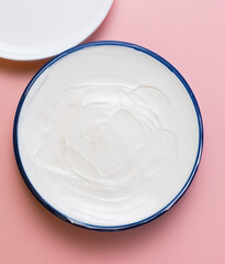 cosmetic cream in a blue jar on a pink background. beauty, relaxation and face and body care concept