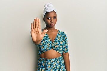 Young african woman wearing hair turban and african style doing stop sing with palm of the hand. warning expression with negative and serious gesture on the face.