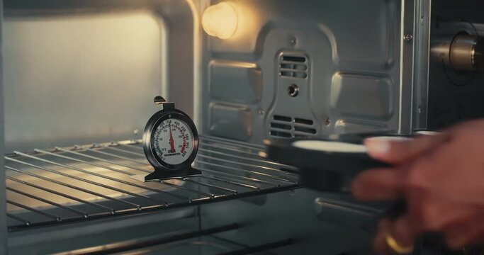 Close up oven with baking tray woman puts cakes inside