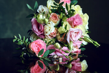 elegant wedding bouquet of white and pink rose flowers. gold wedding rings on the table. preparing for the wedding ceremony