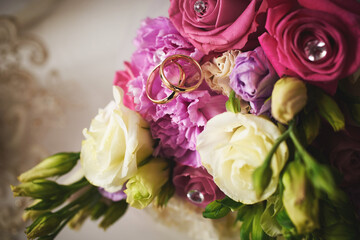 elegant wedding bouquet of white and pink rose flowers. gold wedding rings on the table. preparing for the wedding ceremony