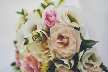 elegant wedding bouquet of white and pink rose flowers. gold wedding rings on the table. preparing for the wedding ceremony