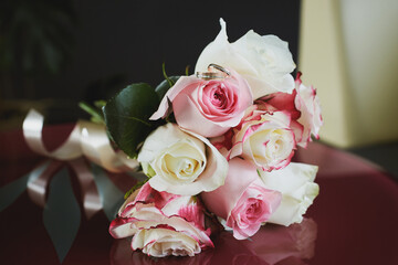 elegant wedding bouquet of white and pink rose flowers. gold wedding rings on the table. preparing for the wedding ceremony