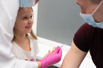 Obraz premium To encourage the girl, before the injection, the nurse suggested that she should try the injections herself. Preventive vaccine for young children.