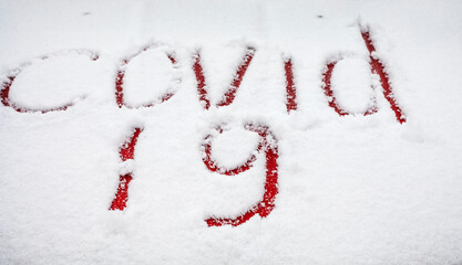 covid -19 written with a finger in the snow on the hood of a red car, lockdown, virus mutation