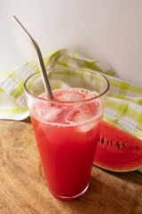 Refreshing watermelon juice with piece of fruit in the background