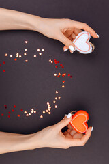 Top view of young girl's hands are holding red and white hearts. around candy from red hearts. Grey background. Valentine's Day. Love around. Copy space