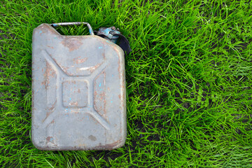 A gray metal canister lies on the green grass. The relevance of nature pollution.