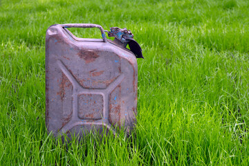 Metal fuel canister on green grass. Symbol of environmental pollution.