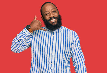 Fototapeta premium Young african american man wearing business shirt smiling doing phone gesture with hand and fingers like talking on the telephone. communicating concepts.