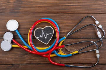 Workplace of a doctor. Colorful Stethoscopes and little heart on wooden desk background - Healthcare concept