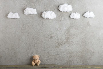 Background with toy bear. Wooden desk, concrete wall and cotton clouds. Fairy tale concept