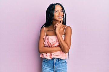 Beautiful hispanic woman wearing casual clothes smiling looking confident at the camera with crossed arms and hand on chin. thinking positive.