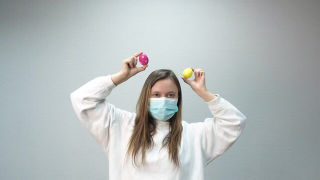 Funny woman in medical mask dancing with easter eggs. Easter holidays celebrating, covid-19 quarantine and pandemic