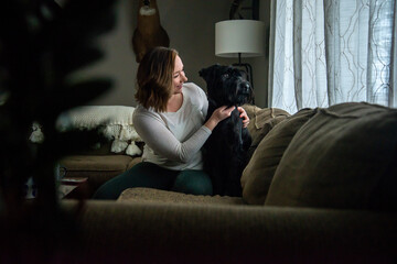Obraz premium Woman petting dog in living room