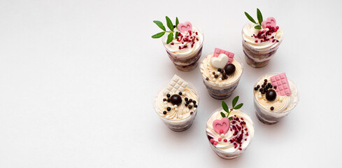 Sweet small homemade trifle dessert with custard, chocolate, nuts and fruits and decorations and cream cheese.