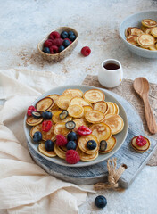 mini pancakes with berries and honey on a plate