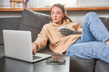Woman with artificial limb relaxing on a couch at home