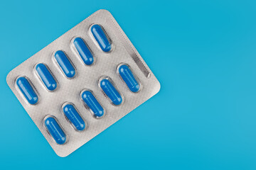 Pharmacy theme, blue pills in capsules, blue background, medicine. Space for text