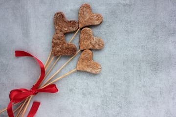 Heart shaped cookies on a stick on a gray concrete background. Overhead view of homemade Valentines treats. Creative gift. Flat lay, copy space. Selective focus